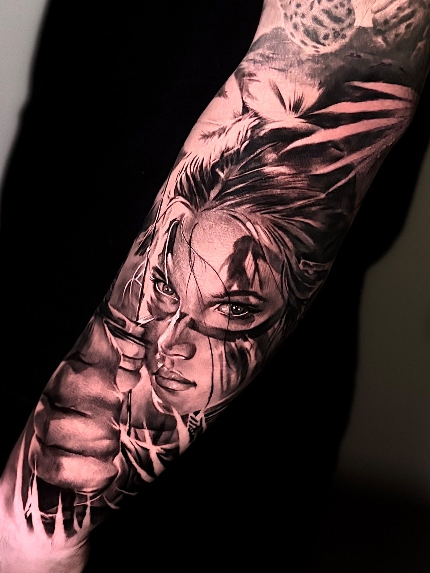 Ritratto di donna tra piume e foglie, tatuaggio realistico sull'avambraccio