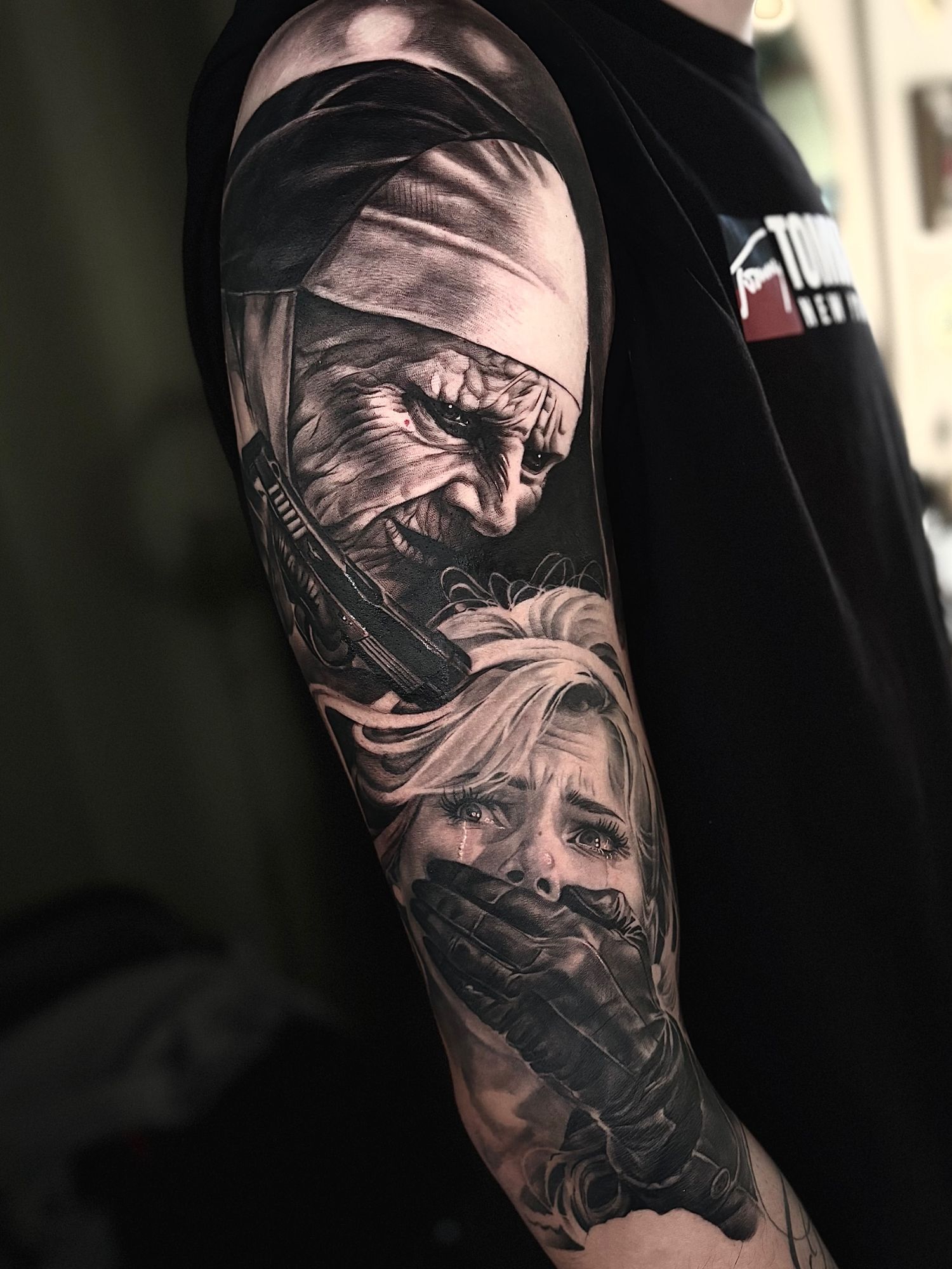 Suora con una pistola e una ragazza con la bocca coperta, tatuaggio horror sul braccio